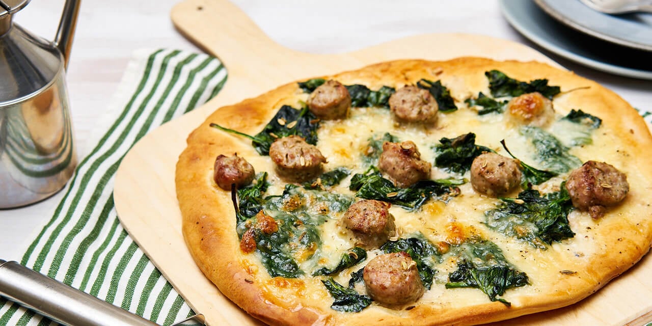 Pizza met stukjes worst en verse spinazie 
