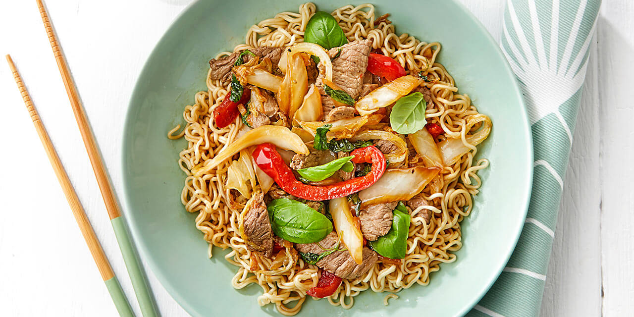 Wok van gemarineerd rundvlees met basilicum en noedels