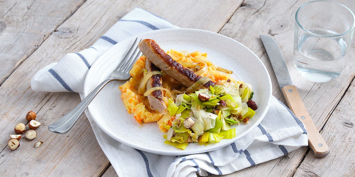 Stoemp de carottes, poireaux aux noisettes, chipolata et sauce à l’oignon